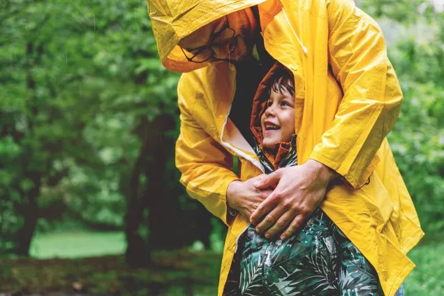 papa protège l'enfant de la pluie avec son manteau
